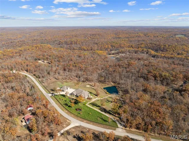 Aerial view of property and surrounding area with a heavily wooded area and a large body of water