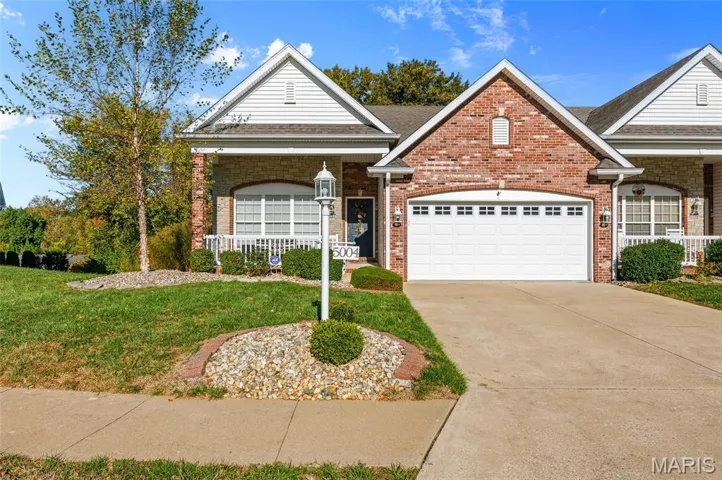 View of front of house with a front lawn, a porch, brick siding, driveway, and a garage