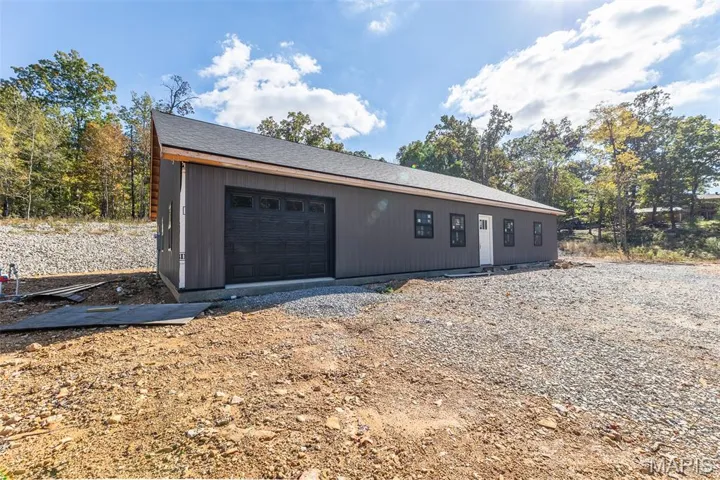 View of front facade with a garage, roof with shingles, and driveway