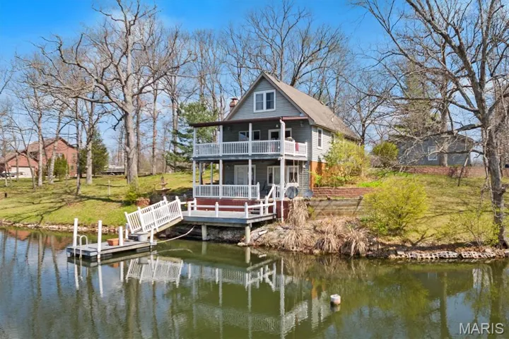 Back of house featuring a water view, a chimney, a yard, and a porch