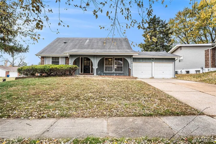 View of front of house with a porch, a garage, concrete driveway, a front lawn, and brick siding