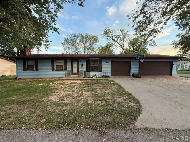 Ranch-style house with concrete driveway, an attached garage, a front yard, and a chimney