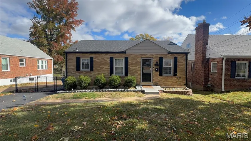 Bungalow-style home with brick siding, a shingled roof, and a gate
