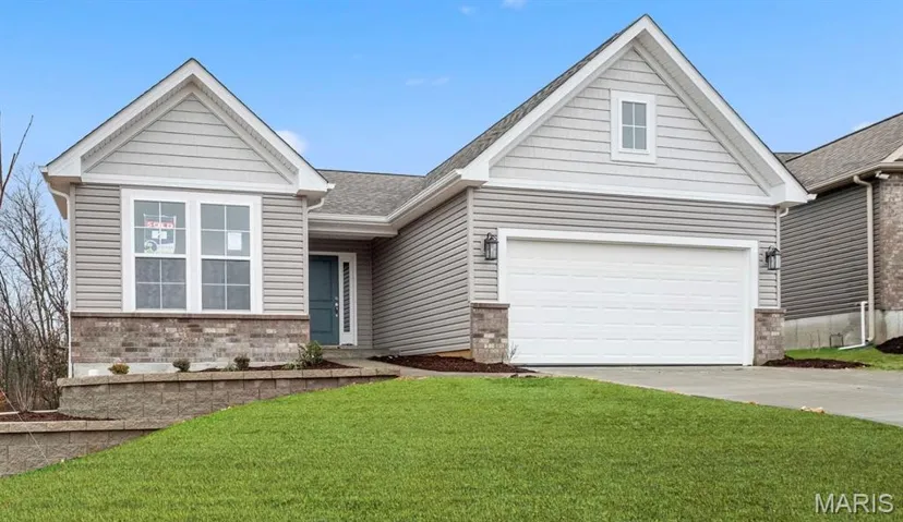 View of front facade featuring a front yard, a garage, driveway, brick siding, and a shingled roof