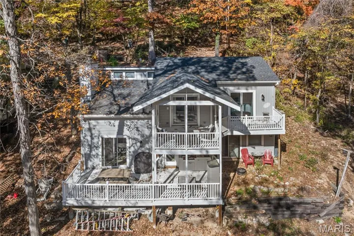 Back of property with roof with shingles and a balcony