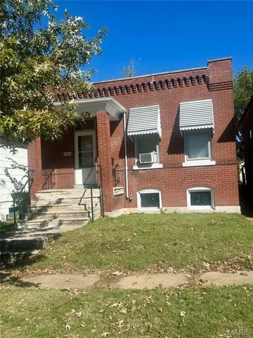 Front view of home with brick exterior and front yard.