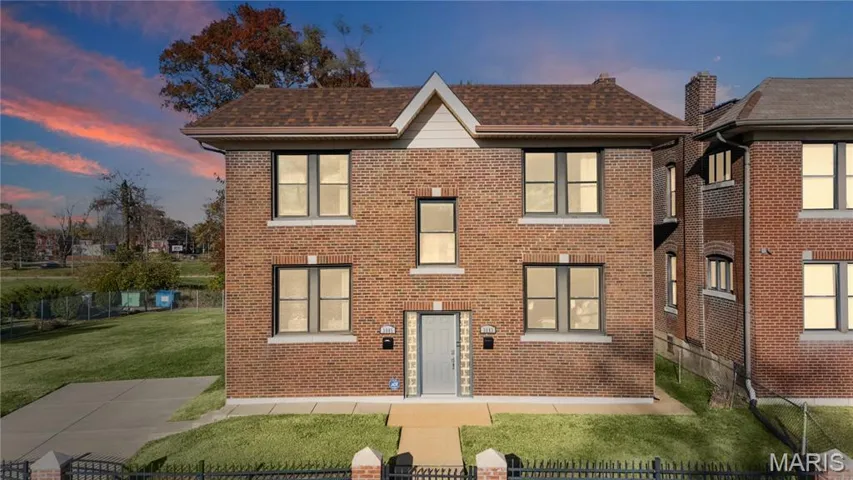 View of front of home with brick siding, roof with shingles, and a fenced front yard