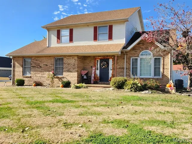 Traditional-style house featuring covered porch, a front lawn, brick siding, and a shingled roof