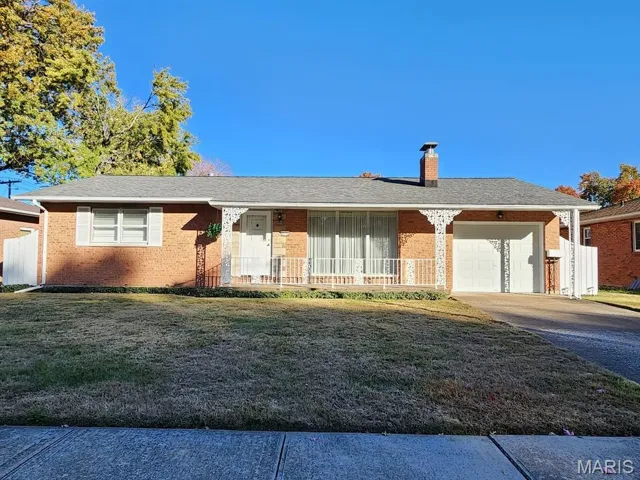 Ranch-style home featuring a front yard, brick siding, an attached garage, a chimney, and covered porch
