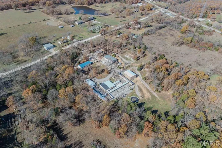 Aerial view of property and surrounding area with 5 large metal buildings rural landscape