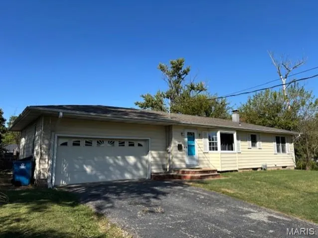 Single story home featuring a front yard, driveway, and an attached garage