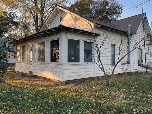View of side of home featuring a metal roof, a lawn, and cooling unit