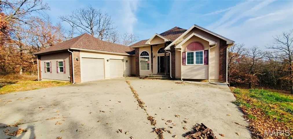 View of front of home with driveway, a garage, and roof with shingles