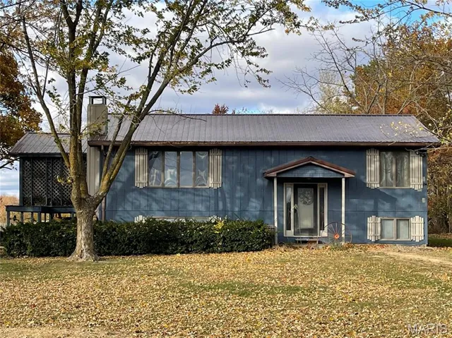 View of front facade with a metal roof, a chimney, and a front yard