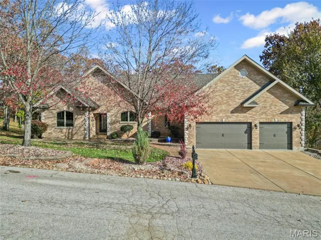 View of front of property with concrete driveway, brick siding, and a garage