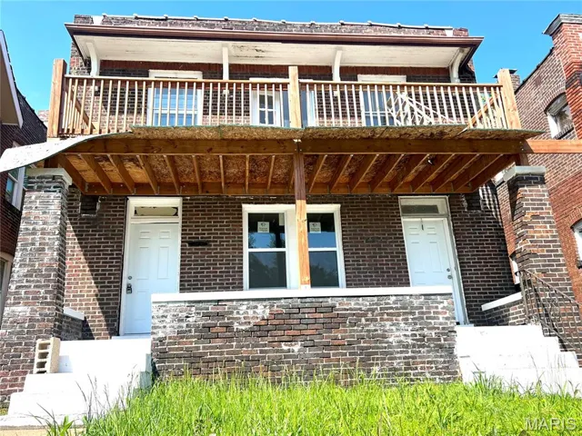 View of front of home with brick siding, a porch, and a balcony