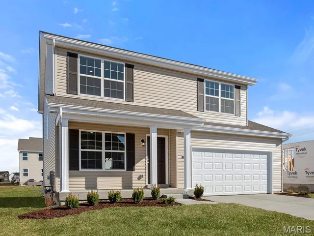 Traditional-style home featuring covered porch, a garage, concrete driveway, and a front yard
