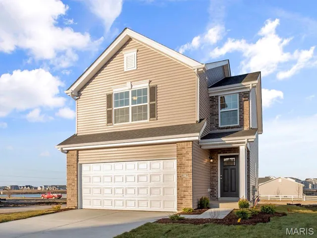 Traditional home with brick siding, an attached garage, and a shingled roof