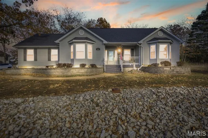 Single story home with a porch and a shingled roof