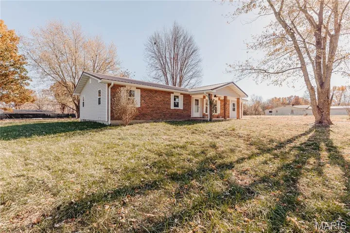 Rear view of property featuring a yard and brick siding