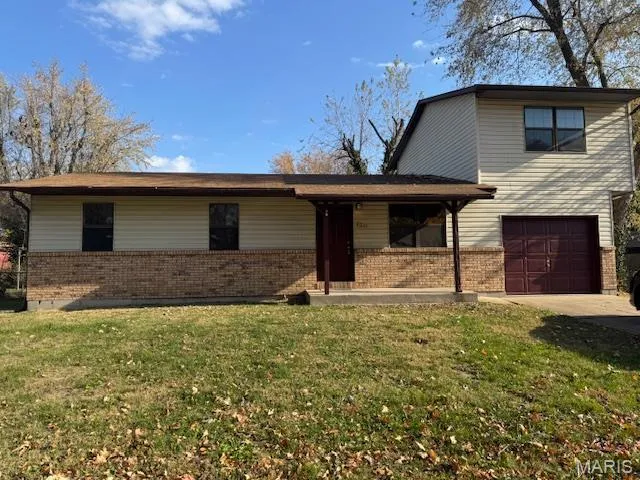 View of front of house featuring a front yard, brick siding, a garage, and driveway