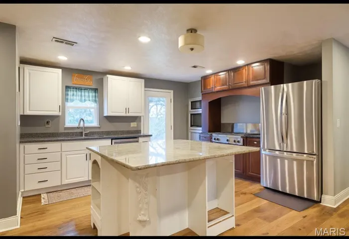 Kitchen featuring dark stone counters, appliances with stainless steel finishes, open shelves, a center island, and recessed lighting