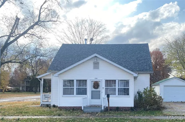 Bungalow-style house featuring a shingled roof, an outdoor structure, and a garage