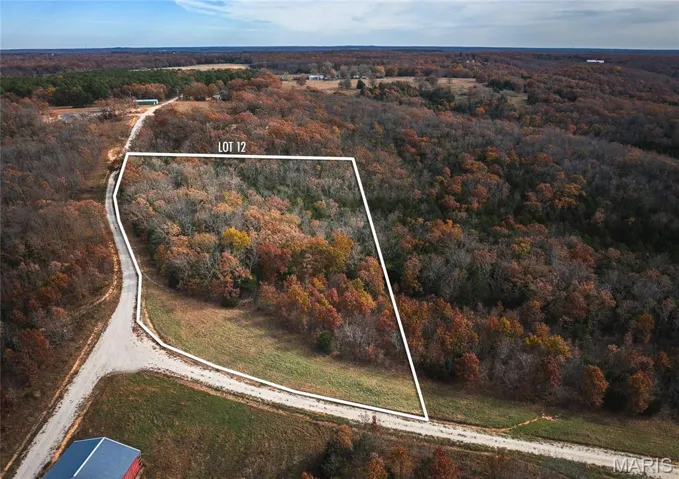 Aerial view of property's location featuring property parcel outlined and a forest