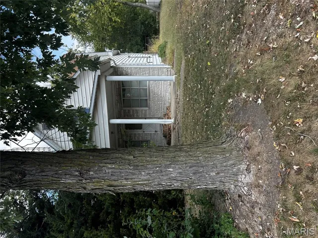 View of side of property with covered porch and a lawn