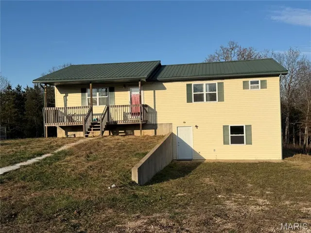 View of front of home with a metal roof, a front lawn, and covered porch