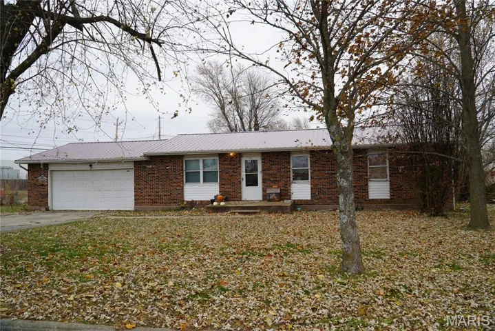 Ranch-style house featuring brick siding, driveway, a metal roof, and an attached garage