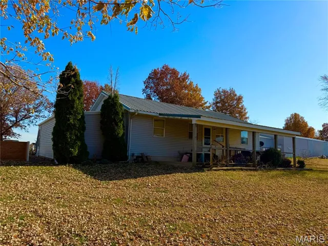 Back of house featuring a metal roof, a lawn, and a porch