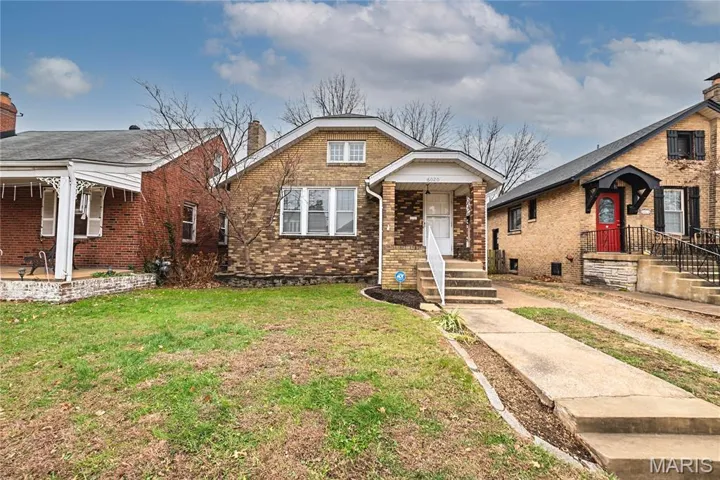 Bungalow featuring brick siding, a chimney, and a front lawn