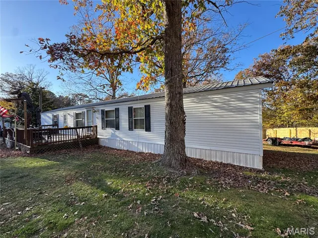 View of home's exterior featuring a lawn, a wooden deck, and a metal roof