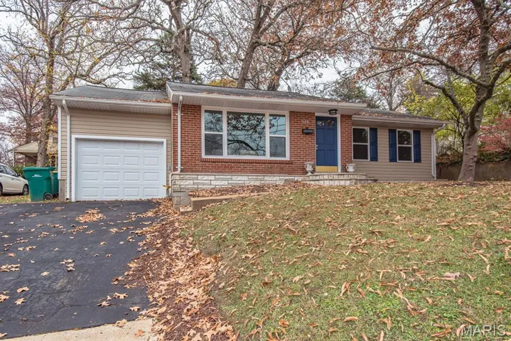 Ranch-style home featuring asphalt driveway, an attached garage, a front yard, and brick siding