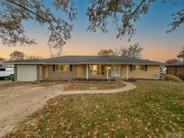 Single story home featuring a garage, a chimney, driveway, a yard, and brick siding