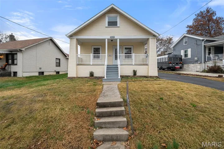 View of front facade with covered porch, stairway, and a front lawn