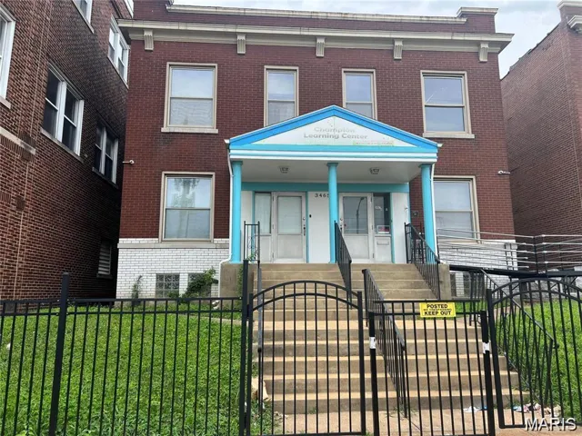 View of front of home featuring a gate, brick siding, and a fenced front yard