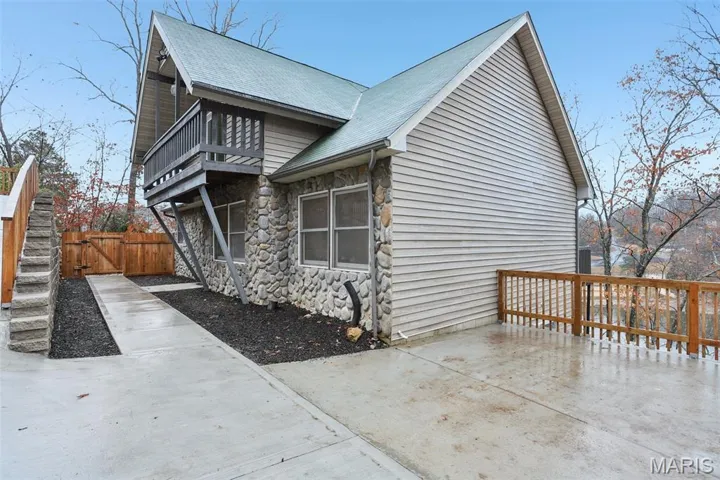 View of side of home with stone siding and a gate