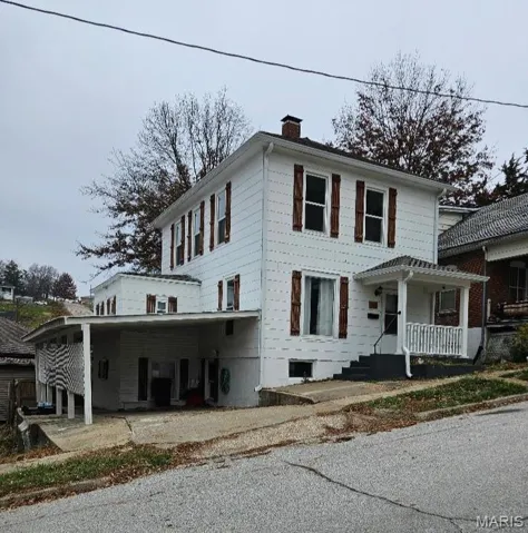 View of front of property with a chimney and a porch