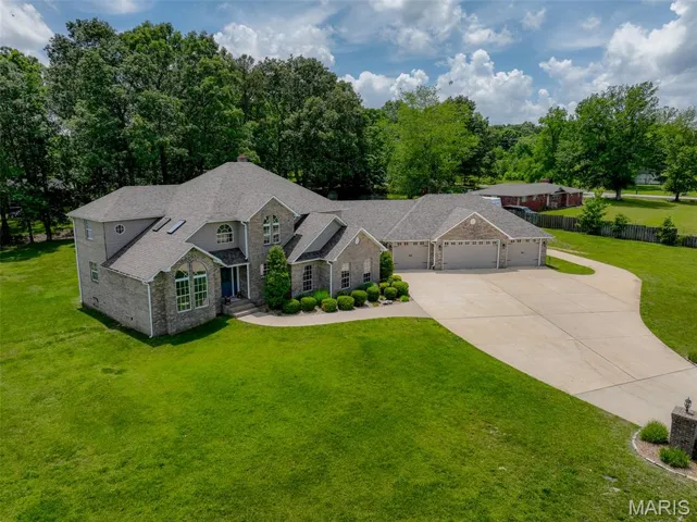 Traditional home with roof with shingles, driveway, brick siding, a garage, and stone siding