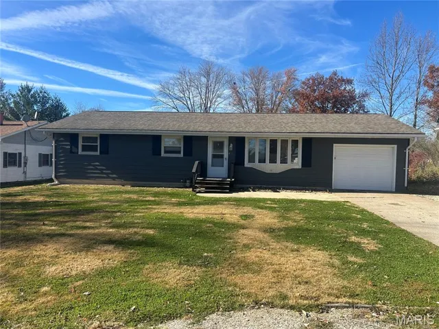 Single story home featuring a front yard, driveway, an attached garage, and roof with shingles