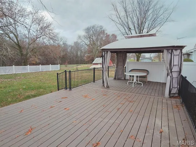 Wooden terrace with a gazebo and a fenced backyard