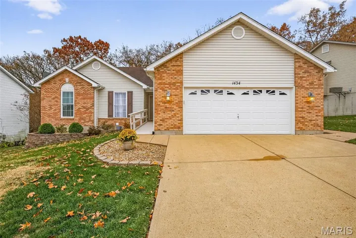 Ranch-style house featuring concrete driveway, a front yard, brick siding, and a garage