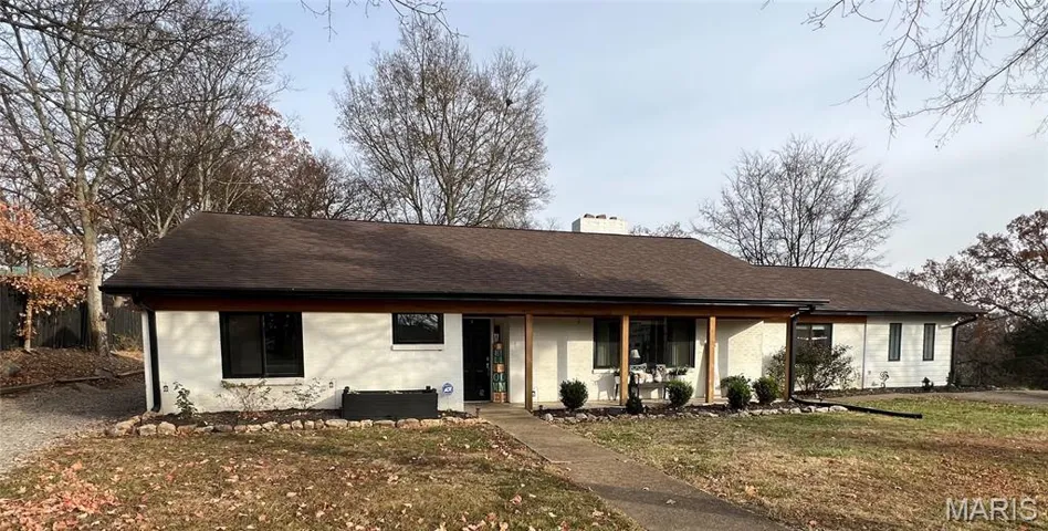 View of front of property with a chimney, a porch, a front lawn, and roof with shingles