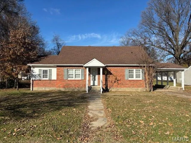 View of front of home with a front lawn, brick siding, and a carport