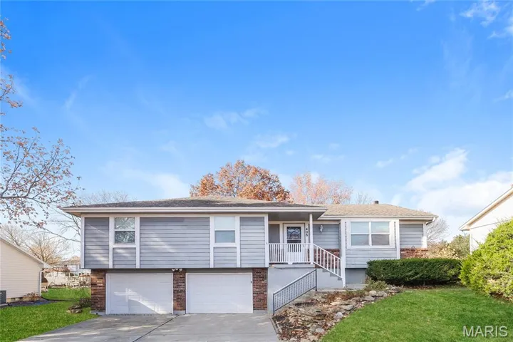 View of front of property featuring brick siding, concrete driveway, a garage, and a front lawn
