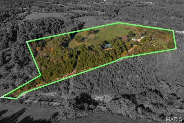 Aerial overview of property's location with a heavily wooded area and property boundaries highlighted