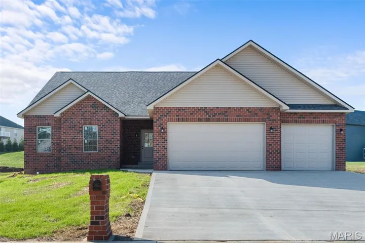 Single story home with a front yard, driveway, an attached garage, and brick siding