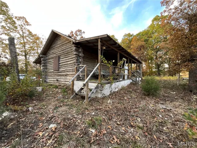 View of property exterior featuring log siding and a wooden deck